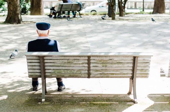 Elderly man sitting alone on a bench.